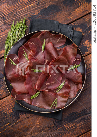 Spanish tapa Cecina meat slices, beef jamon on plate with herbs. wooden background. top view Spanish tapa Cecina meat slices, beef jamon on plate with herbs. wooden background. top view 126392714