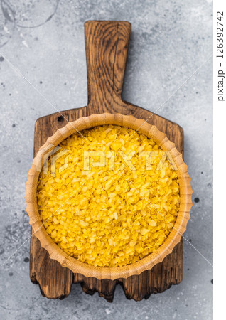 Millet flakes in wooden bowl, rolled millet for porridge and muesli. grey background. top view Millet flakes in wooden bowl, rolled millet for porridge and muesli. grey background. top view 126392742