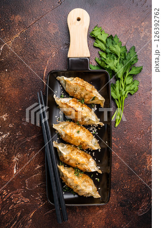 Fried Korean Dumplings on plate with sauce, Dumplings with shrimps and vegetables. brown background. top view Fried Korean Dumplings on plate with sauce, Dumplings with shrimps and vegetables. brown background. top view 126392762