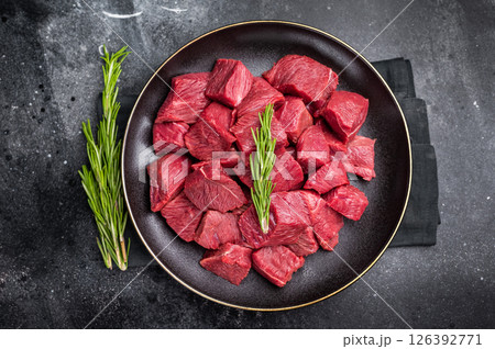 Diced Raw Boar meat, fresh Game Meat in a plate. black background. top view Diced Raw Boar meat, fresh Game Meat in a plate. black background. top view 126392771