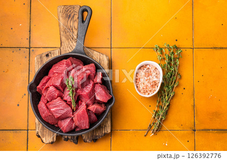 Ready for cooking Diced Elk meat, raw Game Meat in a pan. orange background. top view 126392776