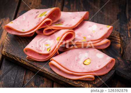 Italian Mortadella sausage slices with pistachios on wooden cutting board. wooden background. top view Italian Mortadella sausage slices with pistachios on wooden cutting board. wooden background. top view 126392876