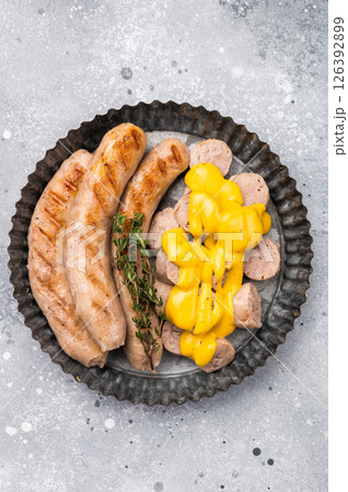 Grilled Bratwurst Sausages with cheese sauce in plate. grey background. top view Grilled Bratwurst Sausages with cheese sauce in plate. grey background. top view 126392899