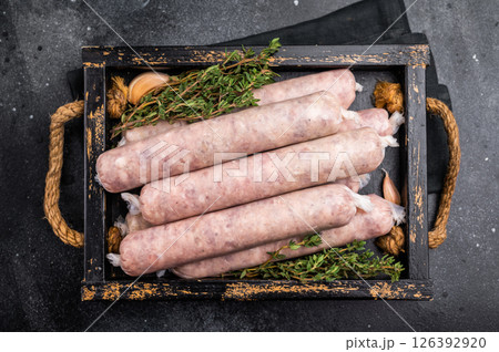 Raw Sausages with minced chicken and turkey meat with herbs in wooden tray. black background. top view 126392920