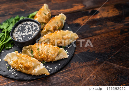 Fried Gyoza on plate with sauce, Japanese Dumplings with shrimps and vegetables. wooden background. top view 126392922