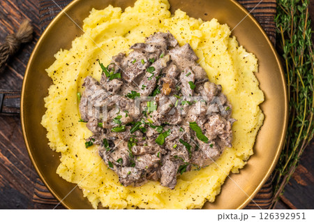 Beef Stroganoff over mashed potatoes with creamy sauce in a plate. wooden background. top view Beef Stroganoff over mashed potatoes with creamy sauce in a plate. wooden background. top view 126392951