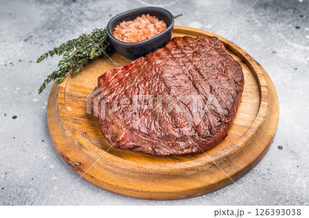 Perfectly grilled top sirloin steak, seared to a juicy finish and garnished with fresh herbs for an irresistible flavor. grey background. top view 126393038