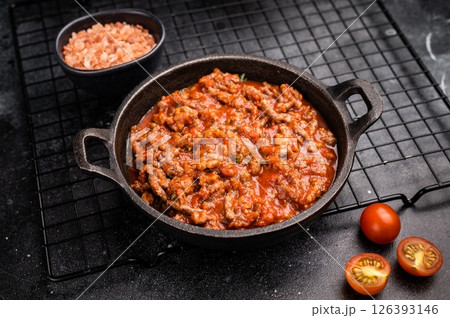 Bolognese sauce with minced beef, tomato paste and herbs in a skillet. black background. top view 126393146