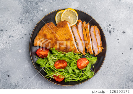 Fried Weiner schnitzel steak, veal breaded meat with salad on a plate. grey background. top view Fried Weiner schnitzel steak, veal breaded meat with salad on a plate. grey background. top view 126393172