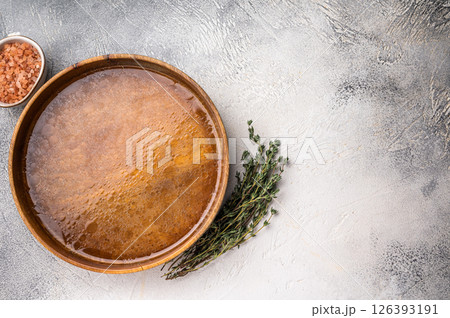 Chicken Bouillon or Broth in a wooden plate. white background. top view Chicken Bouillon or Broth in a wooden plate. white background. top view 126393191