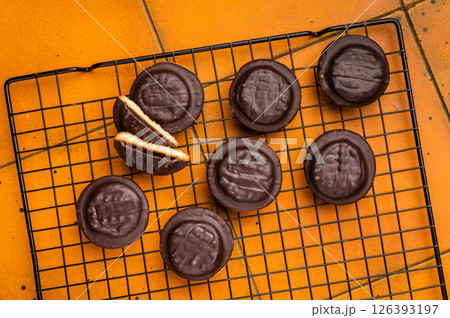 Fresh cooked Jaffa Cookies covered with chocolate and filled with jam on rack. orange background. top view 126393197