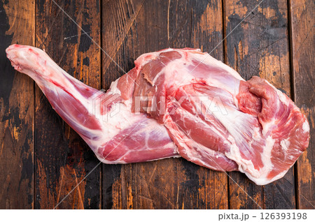 Juicy raw goat shoulder cut, showcasing its vibrant color and texture, perfect for grilling or braising. wooden background. top view 126393198