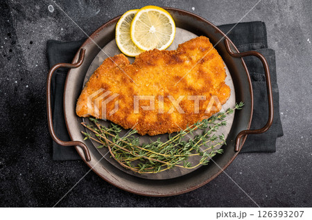 German Wiener schnitzel steak, breaded pork fillet meat. black background. top view 126393207