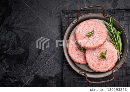 Freshly formed raw meat patty with herbs for burgers, perfect for grilling or frying to satisfy your cravings. black background. top view Freshly formed raw meat patty with herbs for burgers, perfect for grilling or frying to satisfy your cravings. black background. top view 126393258