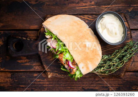 Doner kebab with grilled chicken meat, salad, tomato, onion in pita bread on wooden board. wooden background. top view Doner kebab with grilled chicken meat, salad, tomato, onion in pita bread on wooden board. wooden background. top view 126393260