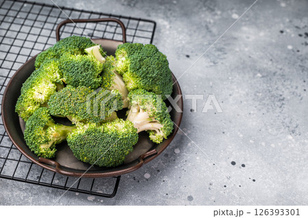 Green fresh broccoli pieces in a steel tray. grey background. top view Green fresh broccoli pieces in a steel tray. grey background. top view 126393301