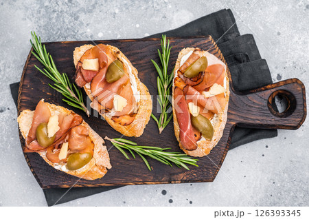 Tapa with Jamon cured ham, parmesan cheese and olives. grey background. top view Tapa with Jamon cured ham, parmesan cheese and olives. grey background. top view 126393345