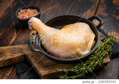 Raw farm chicken leg in a skillet ready for cooking, poultry fresh meat on wooden background, top view. Raw farm chicken leg in a skillet ready for cooking, poultry fresh meat on wooden background, top view. 126393541