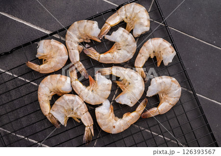 Raw shrimps, headless fresh prawns on a rack. Top view. Black background Raw shrimps, headless fresh prawns on a rack. Top view. Black background 126393567
