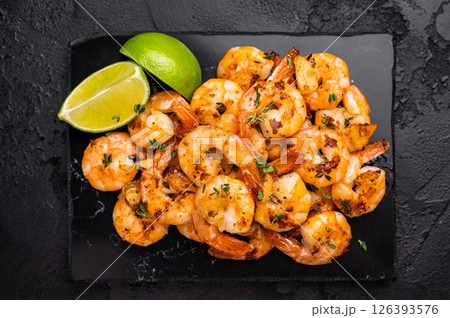 BBQ Roasted spicy Shrimps Prawns with garlic. Black background. Top view BBQ Roasted spicy Shrimps Prawns with garlic. Black background. Top view 126393576