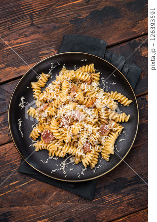 Italian Carbonara pasta topped with crispy bacon bits in a plate. Wooden background. Top view Italian Carbonara pasta topped with crispy bacon bits in a plate. Wooden background. Top view 126393591