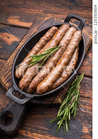 Delicious grilled sausage served with fresh herbs, a mouthwatering addition to any picnic or backyard party. wooden background. top view Delicious grilled sausage served with fresh herbs, a mouthwatering addition to any picnic or backyard party. wooden background. top view 126393604