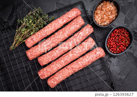 Uncooked Raw Cevapcici Sausage, fresh Cevapi from mince beef and pork meat on a rack. black background. top view Uncooked Raw Cevapcici Sausage, fresh Cevapi from mince beef and pork meat on a rack. black background. top view 126393627