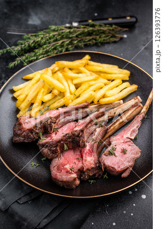 Roast lamb cutlets, mutton meat steaks on plate with french fries. black background. top view Roast lamb cutlets, mutton meat steaks on plate with french fries. black background. top view 126393776