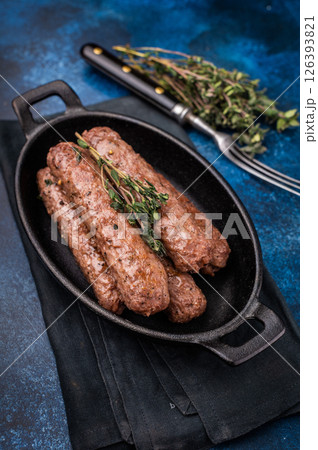 Grilled Cevapcici Sausage, roasted Cevapi from mince beef and pork meat in a skillet. blue background. top view Grilled Cevapcici Sausage, roasted Cevapi from mince beef and pork meat in a skillet. blue background. top view 126393821