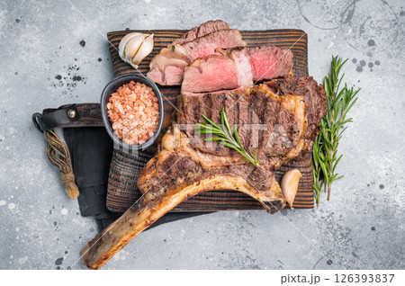 BBQ fried Tomahawk beef steak, grilled marbled rib eye with bone on wooden board. grey background. top view BBQ fried Tomahawk beef steak, grilled marbled rib eye with bone on wooden board. grey background. top view 126393837