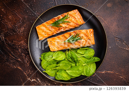 Grilled salmon fillet with spinach, fish steak in a plate. brown background. top view Grilled salmon fillet with spinach, fish steak in a plate. brown background. top view 126393839
