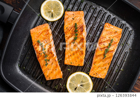 Pan fried salmon fillet steaks with thyme and lemon, fresh fish. wooden background. top view Pan fried salmon fillet steaks with thyme and lemon, fresh fish. wooden background. top view 126393844
