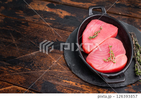 Vibrant raw tuna steak, showcasing its deep red hue, an essential ingredient for sushi enthusiasts and seafood connoisseurs. wooden background. top view Vibrant raw tuna steak, showcasing its deep red hue, an essential ingredient for sushi enthusiasts and seafood connoisseurs. wooden background. top view 126393857