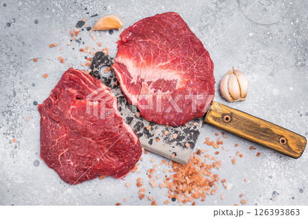 Raw beef cheeks on butcher meat cleaver. grey background. top view Raw beef cheeks on butcher meat cleaver. grey background. top view 126393863