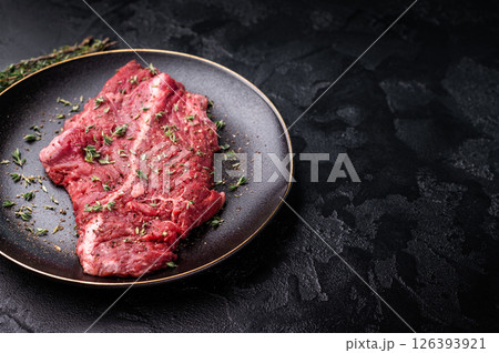 Raw hanger tender beef steak, skirt steak on plate with herbs and spices. black background. top view 126393921