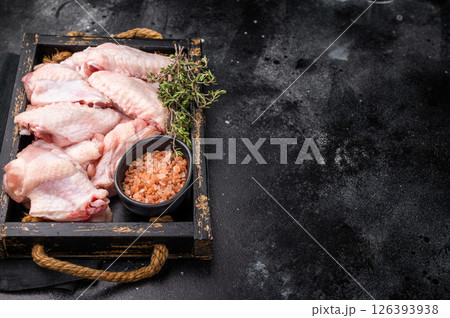 Beautifully arranged raw chicken wings, ready to soak up your favorite marinades for a tasty culinary adventure. black background. top view 126393938