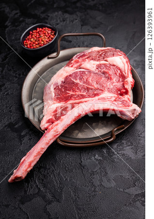 Raw tomahawk steak with marbling, fresh rib eye with bone. black background. top view Raw tomahawk steak with marbling, fresh rib eye with bone. black background. top view 126393961