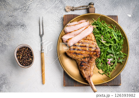 Mouthwatering grilled pork chop with a stunning presentation, perfect for serving at special occasions. grey background. top view Mouthwatering grilled pork chop with a stunning presentation, perfect for serving at special occasions. grey background. top view 126393982