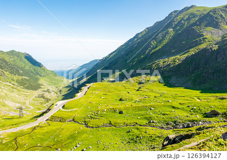 transfagarasan road winding uphill. fagaras ridge. travel destination in romania mountain landscape. sunny day in summer. view in to the valley. blue sky with cloud 126394127