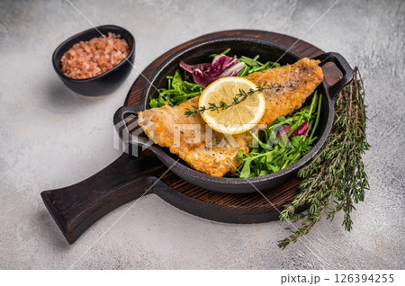 Fried Haddock fish fillet in a pan. grey background. top view Fried Haddock fish fillet in a pan. grey background. top view 126394255