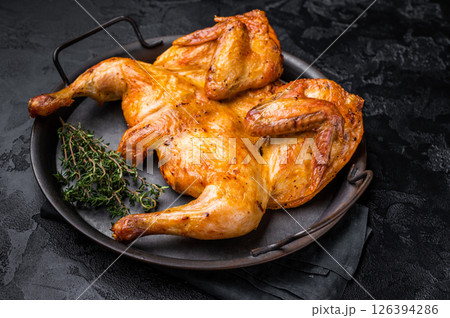 Roasted chicken Tabaka with herbs and spices, poultry meat on steel tray. black background. top view 126394286