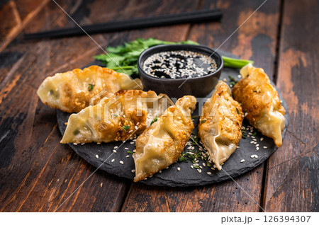 Fried Gyoza on plate with sauce, Japanese Dumplings with shrimps and vegetables. wooden background. top view 126394307