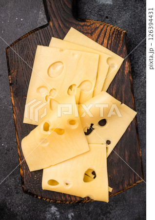 Swiss emmental cheese slices on wooden cutting board. black background. top view 126394431