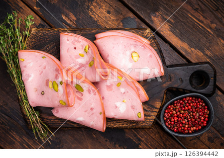 Italian Mortadella sausage slices with pistachios on wooden cutting board. wooden background. top view Italian Mortadella sausage slices with pistachios on wooden cutting board. wooden background. top view 126394442