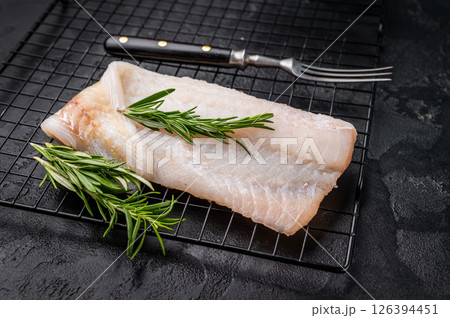 Uncooked Atlantic cod fillet, raw fish ready to be seasoned and transformed into a delicious meal. black background. top view Uncooked Atlantic cod fillet, raw fish ready to be seasoned and transformed into a delicious meal. black background. top view 126394451