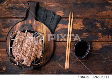 Flavorful yakiniku with juicy wagyu beef slices cooked right at the table. wooden background. top view 126394513