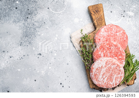 Frozen raw Hamburger beef Patty, uncooked mincemeat. grey background. top view 126394593
