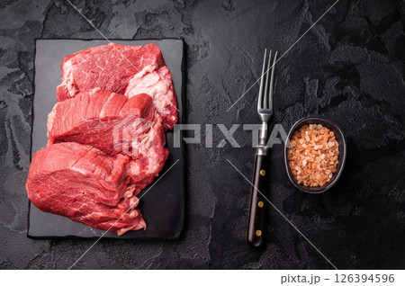 Raw beef boneless shank shin presented with herbs and spices, inspiring bold flavors and unique recipes for adventurous home cooks. black background. top view 126394596