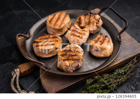 Flavorful grilled pork tenderloin cutlets, expertly cooked to perfection, promising a delicious dining experience. black background. top view Flavorful grilled pork tenderloin cutlets, expertly cooked to perfection, promising a delicious dining experience. black background. top view 126394605