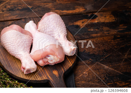Uncooked poultry drumsticks, raw chicken legs ideal for your favorite recipes, waiting to be seasoned and cooked to perfection. wooden background. top view Uncooked poultry drumsticks, raw chicken legs ideal for your favorite recipes, waiting to be seasoned and cooked to perfection. wooden background. top view 126394608